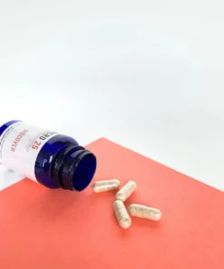 Close up of uniform clear vegetable capsules filled with a finely ground Discover blend botanical powder beside a bottle